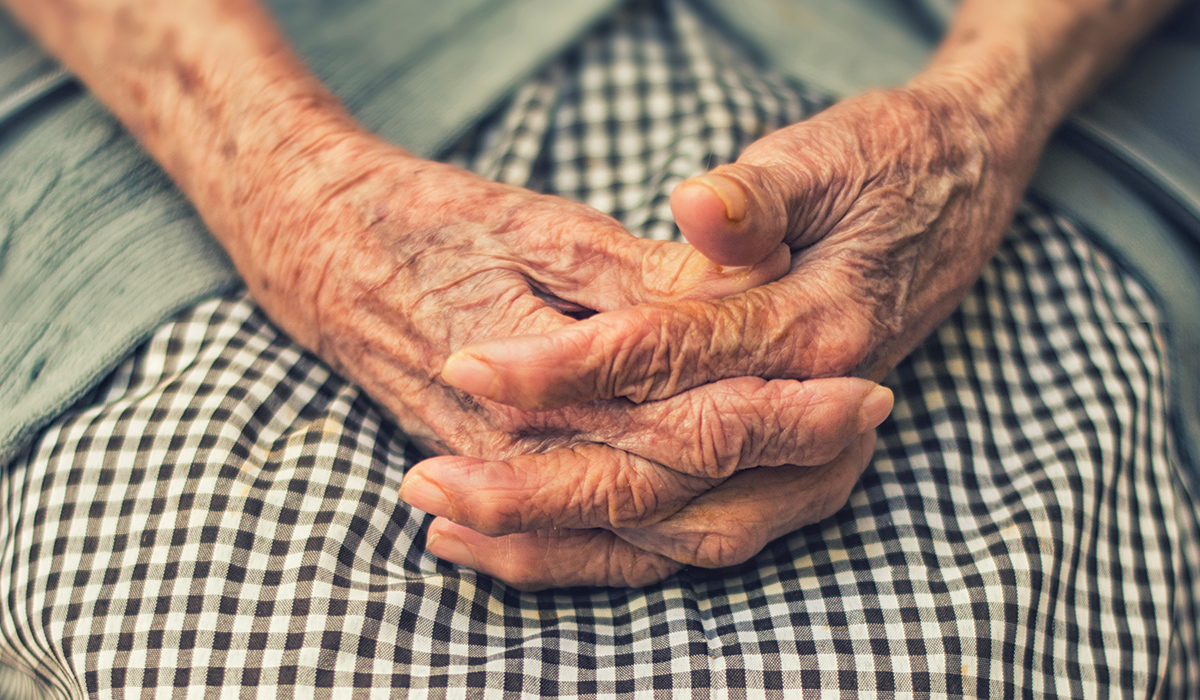 an elderly persons hands clasped on their lap