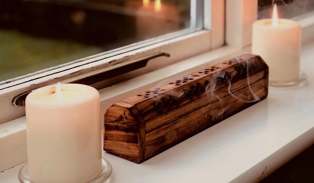 two candles and a wooden box on a window sill