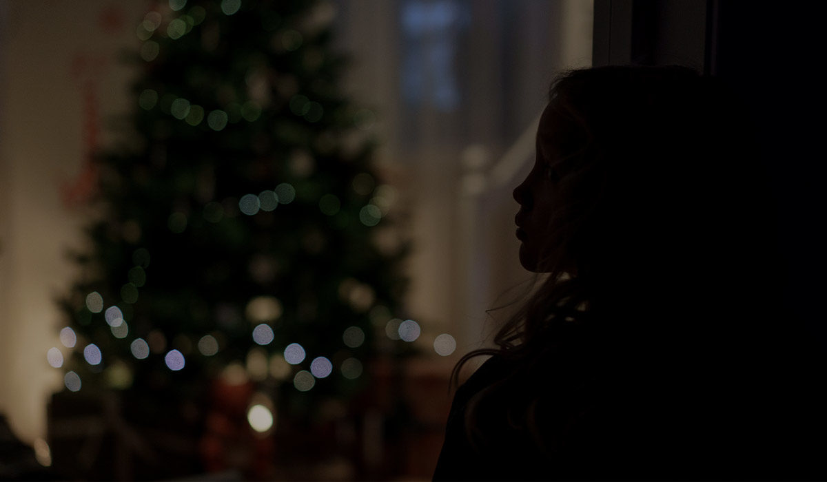 a silhouette of a young girl looking at a christmas tree